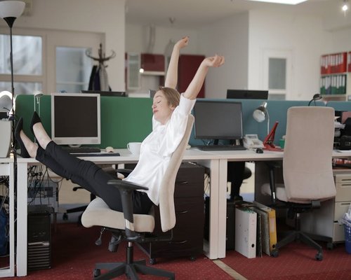 Young man stretching his arms and neck near a work desk to relieve tension